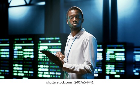 Computer scientist using tablet to check server room security features protecting against unauthorized access, data breaches, distributed denial of service attacks and other cybersecurity threats - Powered by Shutterstock