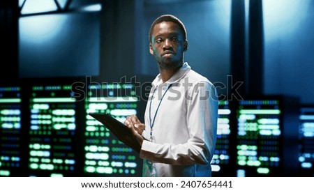 Computer scientist using tablet to check server room security features protecting against unauthorized access, data breaches, distributed denial of service attacks and other cybersecurity threats