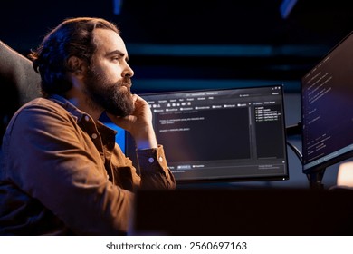 Computer scientist working from home developing software in JavaScript programming language. System administrator in living room inspecting lines of code on desktop PC monitor
