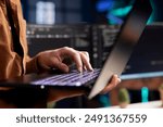 Computer scientist working from home using laptop, testing and deploying programs. Programmer checking code displayed on desktop PC screens in blurry background, close up shot