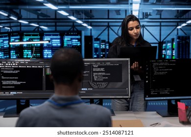 Computer scientists in data center running system diagnostic tests on laptop to fix problems. IT professionals in server room deploying error checking utilities on notebook to fix network issues