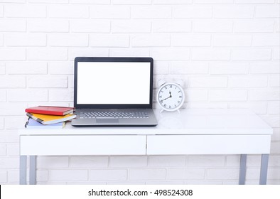 Computer screen with copy space and notebooks near brick wall. Selective focus 
