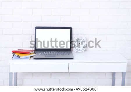 Computer screen with copy space and notebooks near brick wall. Selective focus 