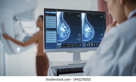 Экран компьютера в больничной радиологической палате: красивая многонациональная взрослая женщина, стоящая топлесс, проходящая процедуру маммографического скрининга. Экран, показывающий маммограмму плотных тканей молочной железы.