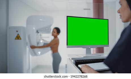 Computer Screen In Hospital Radiology Room: Beautiful Multiethnic Young Woman Standing Topless Undergoing Mammography Screening Procedure. Screen Shows Green Mock-up Template Screen.