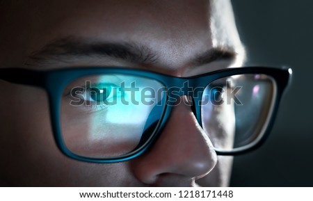 Computer screen light reflect from glasses. Close up of eyes. Business man, coder or programmer working late at night with laptop. Thoughtful focused guy in dark. Reflection of monitor.