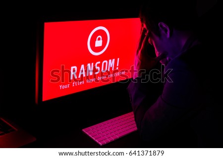 Computer screen with ransomware attack file encrypted alerts in red, a man get stress with keyboard in a dark room, ideal for online security failure and digital crime, long exposure selective focus