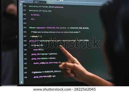 Computer screen showing C language source code with syntax highlighting and line numbers while a finger points at a function, programming and software development detail