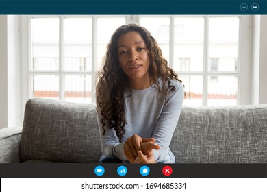 Computer Screen View African Woman Sit On Couch Looking At Webcam, Share News With Friend, Applicant Pass Job Interview By Videoconference App, Communicates With Employer From Home, Video Call Concept