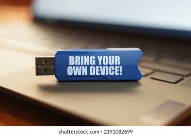 Computer and security concept. On the laptop keyboard is a flash drive with the inscription - BRING YOUR OWN DEVICE