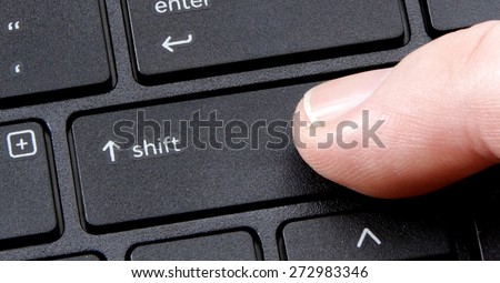 computer shift key with finger pressing button on white background