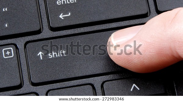 computer shift key with finger pressing button\
on white background
