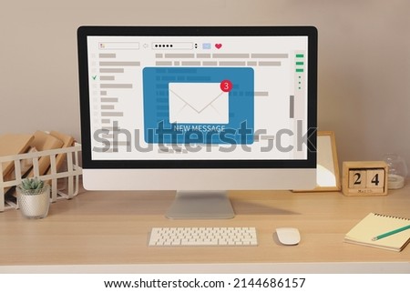Computer with symbol of new unread e-mail messages on screen at workplace