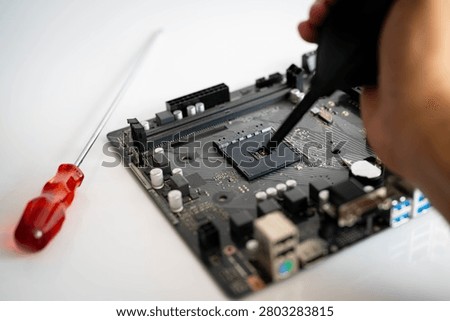 Computer technician cleaning CPU socket on motherboard with air blower during PC maintenance. Concept of hardware repair, computer assembly, electronics service, system upgrade and technology support.