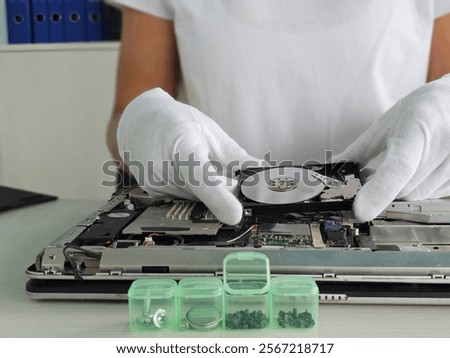 Computer technician performs hard drive replacement on laptop with care at a workshop