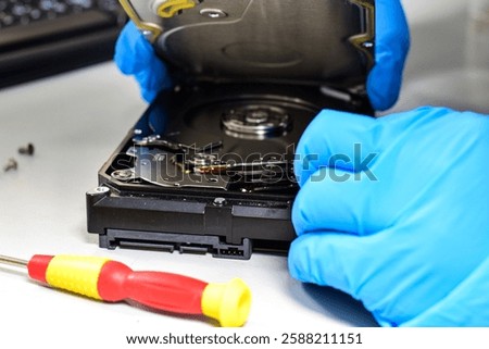 Computer technician wearing gloves with a screwdriver Dismantling and repairing hard disks on a work desk