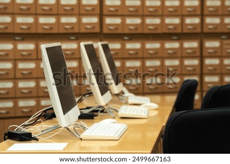 computer terminals in a modern library with blurred catalog cabinets in the background