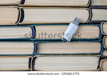 Computer usb drive on the background of a stack of old paper books. Information storage media. Top view with copy space