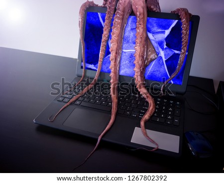 Computer virus concept. Laptop with broken screen seized by disgusting monster with long sticky tentacles.
