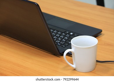 Computer and white cup on the table. 