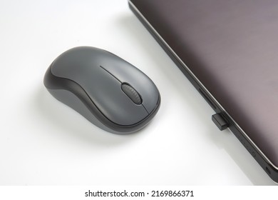 Computer wireless mouse next to a laptop on a white table close-up. electronic personal industry