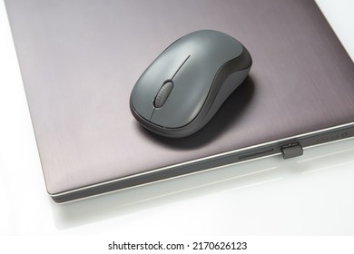 Computer wireless mouse next to a laptop on a white table close-up. electronic personal industry