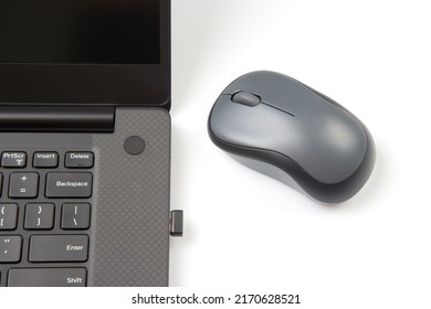 Computer wireless mouse next to a laptop on a white table close-up. electronic personal industry