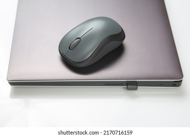 Computer wireless mouse next to a laptop on a white table close-up. electronic personal industry