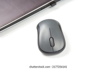 Computer wireless mouse next to a laptop on a white table close-up. electronic personal industry
