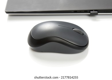 Computer wireless mouse next to a laptop on a white table close-up. electronic personal industry