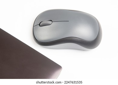 Computer wireless mouse next to a laptop on a white table close-up. electronic personal industry