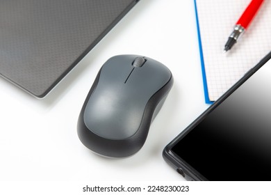 Computer wireless mouse next to a laptop on a white table close-up. electronic personal industry