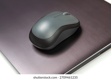 Computer wireless mouse next to a laptop on a white table close-up. electronic personal industry