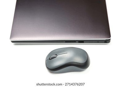 Computer wireless mouse next to a laptop on a white table close-up. electronic personal industry