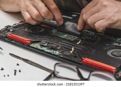 The Computer Wizard Going To Dismantle The Laptop Cooling System To Check And Clean Its Components. The Concept Of Computer Technology, Repair, Technology And Update. Laptop Maintenance. Close Up.