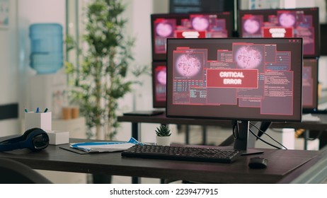Computers displaying critical error message flashing on screen, dealing with hacking threat and computer malware. Empty desk with multiple monitors showing security breach alert.