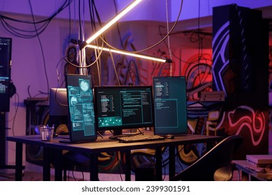 Computers with malicious ransomware running code on screens in abandoned warehouse. Encryption software multiple windows and password hacking activity on monitors in dark room