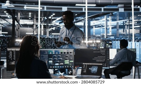 Computing hub team supervisor talking with software programmer working with visual programming system to enhance system health with supervisor overseeing IT specialist assessing equipment issues.