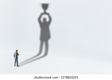 Comtemplating on business success, top performance, winner concept : Businessman looks his shadow raising a trophy cup on the wall, depicts scrutinizing on ways to race and achieve goals and win prize