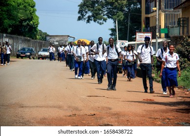 Conakry, Guinea - October 10th 2012: Group of happy teenagers in school uniform walking along a dirt road in Conakry, Guinea, West Africa