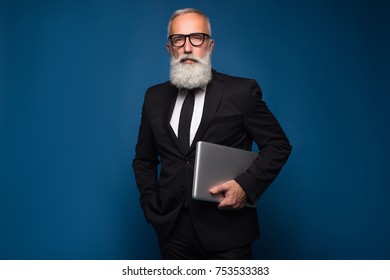 Concentrate bearded senior and business man staying with notebook and working isolated on a blue background. Working business man in straight suit and glasses