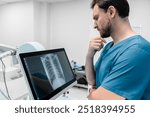 Concentrate male radiologist looks at lung x-ray image in his lab. Doctor examining chest x-ray film of patient at hospital. Lung radiography concept. Modern medical equipment