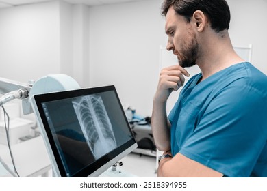 Concentrate male radiologist looks at lung x-ray image in his lab. Doctor examining chest x-ray film of patient at hospital. Lung radiography concept. Modern medical equipment - Powered by Shutterstock