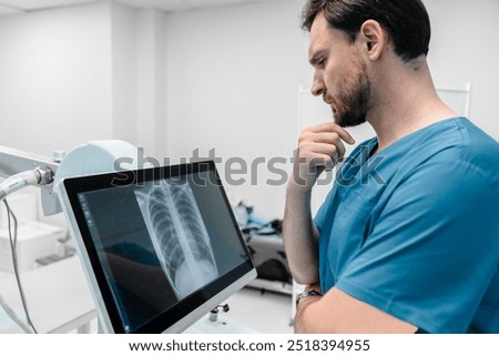 Concentrate male radiologist looks at lung x-ray image in his lab. Doctor examining chest x-ray film of patient at hospital. Lung radiography concept. Modern medical equipment