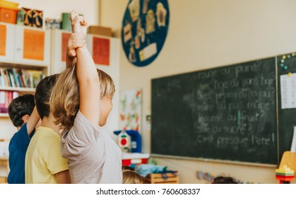 Concentrated 4-5 Year Old Kids In Classroom, Child Raising Hand On Lesson, Back View