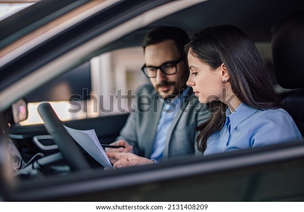 Concentrated adult man, giving instructions to an\
adult female about\
cars.