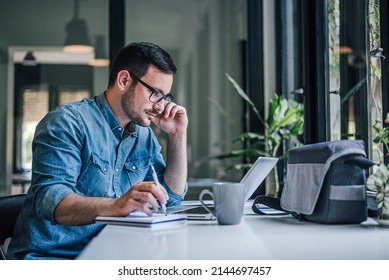 Concentrated adult man, organizing his busy work week in the office. - Shutterstock ID 2144697457