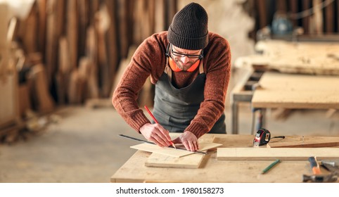 Concentrated Adult Woodworker Marking Wooden Piece With Pencil While Working At Workbench In Joinery Studio