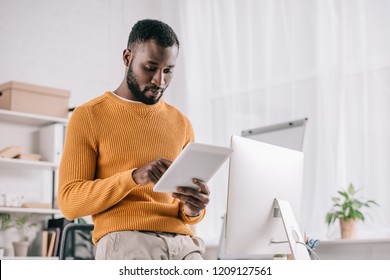 concentrated african american designer in yellow sweater working with digital tablet in modern office - Powered by Shutterstock