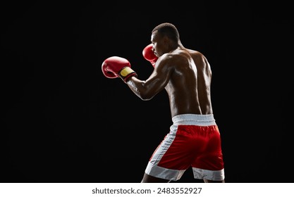 Concentrated African-American man, boxer with sweating shirtless body training, punching isolated on black background. Side view. Concept of professional sport, active lifestyle, body, strength - Powered by Shutterstock